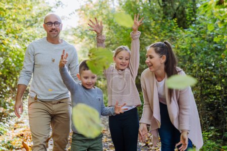 Foto de Familia feliz divirtiéndose con el follaje en el bosque de otoño. - Imagen libre de derechos