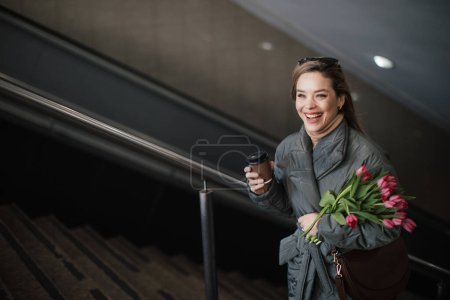 Téléchargez les photos : Jeune femme dans une ville avec un bouquet de tulipes. - en image libre de droit