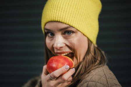 Photo for Portrait of young fashionable woman eating an apple. - Royalty Free Image