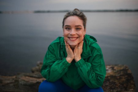 Photo for Portrait of happy woman in sportive clothes resting near a lake. - Royalty Free Image