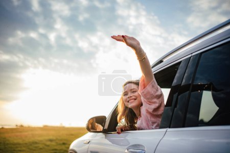 Téléchargez les photos : Femme heureuse conduisant sa nouvelle voiture électrique dans une ville. - en image libre de droit
