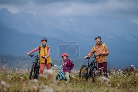 Photo for Young family with little daughter at bicycles, in the middle of autumn nature.Concept of healthy lifestyle. - Royalty Free Image