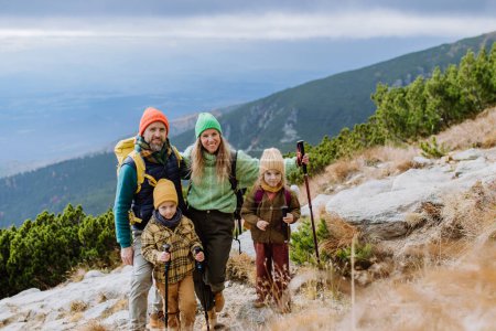 Foto de Retrato de familia feliz con bastones de trekkiing caminando juntos en una montaña de otoño. Senderismo con niños pequeños. - Imagen libre de derechos