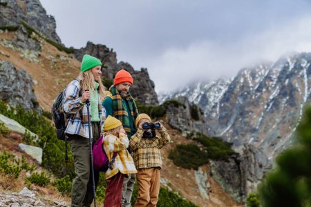 Téléchargez les photos : Portrait de famille heureuse faisant de la randonnée ensemble dans une montagne d'automne. Randonnée avec les jeunes enfants. Petit garçon regardant à travers des jumelles. - en image libre de droit