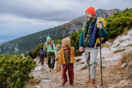 Téléchargez les photos : Portrait de famille heureuse avec bâtons de trekki randonnée ensemble dans une montagne d'automne. Randonnée avec les jeunes enfants. - en image libre de droit
