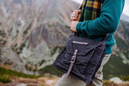 Foto de Primer plano de una bolsa bandolera de denim. Hombre weraring bolso cruzado durante la caminata en una montaña de otoño. - Imagen libre de derechos