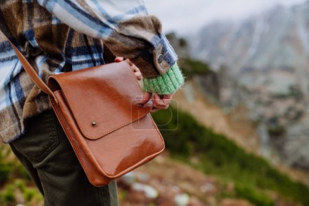 Foto de Primer plano de un bolso bandolera de cuero. Mujer weraring bolso cruzado durante la caminata en una montaña de otoño. - Imagen libre de derechos