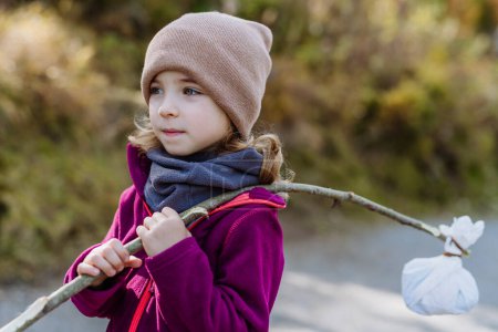 Photo for Portrait of little girl with bindle during autumn hike in mountains. Girl holding stick with cloth carrying snack inside. - Royalty Free Image