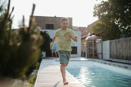 Photo for Young boy running along swimming pool at home. Pool safety with childrens. - Royalty Free Image