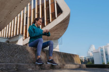 Photo for Side view of sporty woman checking her performance on smartwach after workout session. Woman using smartwatch to sending text message, calling. - Royalty Free Image