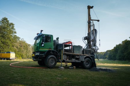 Photo for Water well drilling rig, truck preparing to boring dowin into the earth. A rotary drill rig using bits to bore into ground and loosing the soil and rocks. Drilling machine, equipment using water to - Royalty Free Image
