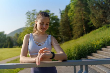 Photo for Potrait of sporty woman checking her performance on smartwach after workout session. Woman using smartwatch to sending text message, calling. - Royalty Free Image
