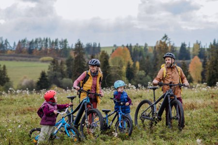 Foto de Familia joven con niños pequeños en bicicletas, en medio de la naturaleza otoñal.Concepto de estilo de vida saludable. - Imagen libre de derechos