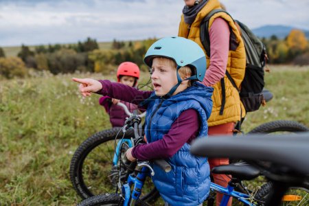 Photo for Portrait of little boy preparing for bicycle ride in nature. Cute boy pointing on something in the distance with finger. - Royalty Free Image