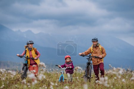Téléchargez les photos : Vue de face de la jeune famille avec petite fille à vélo, au milieu de la nature automnale.Concept de mode de vie sain. - en image libre de droit