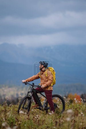 Téléchargez les photos : Homme actif à vélo au milieu de la nature automnale, admirer les montagnes. Concept de mode de vie sain. - en image libre de droit