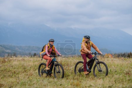 Foto de Yung feliz pareja en las bicicletas, en medio de la naturaleza de otoño. Pareja casada pasando sus lunas de miel senderismo, mochilero, visitando parques nacionales. - Imagen libre de derechos