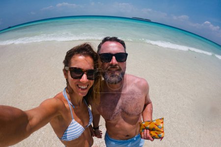 Photo for Portrait of beautiful couple on romantic beach vacation. Newlyweds on their honeymoon by the sea on the island of Zanzibar. Fisheye shot with copy space. - Royalty Free Image