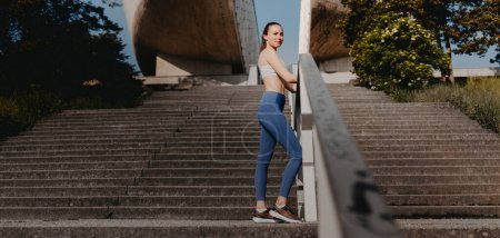 Photo for Portrait of sporty woman running on the concrete stairs in city park. Female athlete in sportswear doing stair workout outside. Healty lifestyle concept. Banner with copyspace. - Royalty Free Image