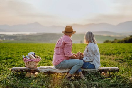 Téléchargez les photos : Couple âgé assis à la prairie et avoir un moment romantique à la nature d'automne. Épouses âgées regardant un paysage serein, bénéficiant d'une belle vue à High Tatras. - en image libre de droit