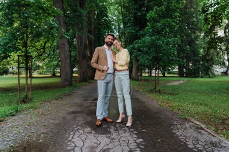 Téléchargez les photos : Jeune couple marié en promenade dans le parc de la ville après le travail. Couple de travail passe du temps à l'extérieur après une longue journée de travail. Concept d'équilibre travail-vie personnelle, - en image libre de droit