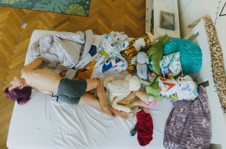 Photo for Top view of siblings lying on the bed and watching television. The children spending time indoors while raining during summer break. Longer screen time during holidays. - Royalty Free Image