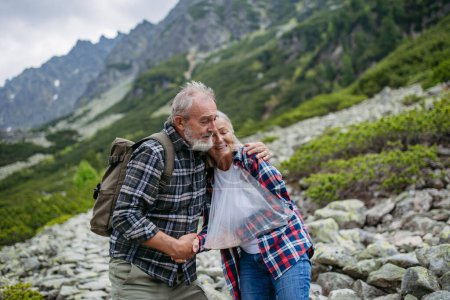 Téléchargez les photos : Un aîné aidant une femme blessée. Une femme âgée s'est blessée au bras lors d'une randonnée dans les montagnes. Touriste est allé hors des sentiers et est tombé. - en image libre de droit