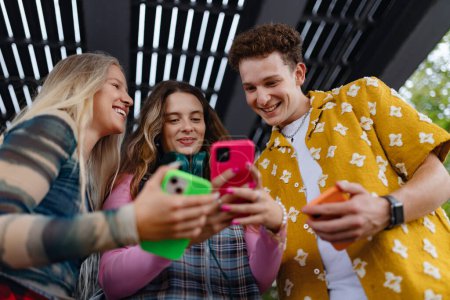 Photo for Generation z students hanging out together outdoors in the city. Young stylish zoomers are online, using smartphones, social media, taking selfies. Concept of power of friendship and social strength - Royalty Free Image
