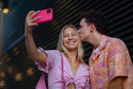 Téléchargez les photos : Couple Gen Z en tenue rose prenant selfie avant d'aller au cinéma pour regarder des films. La jeune fille et le garçon zoomer regardé un film abordant le sujet des femmes, sa position dans le monde, et l'image du corps - en image libre de droit