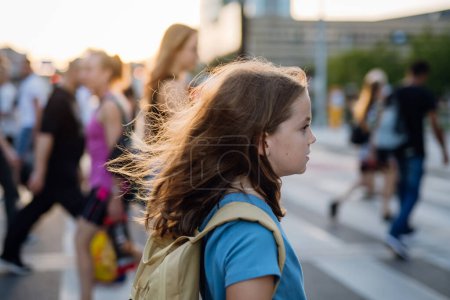 Foto de Vista lateral de una chica con una mochila cruzando el paso peatonal en su camino a la escuela. Concepto de regreso a la escuela. - Imagen libre de derechos