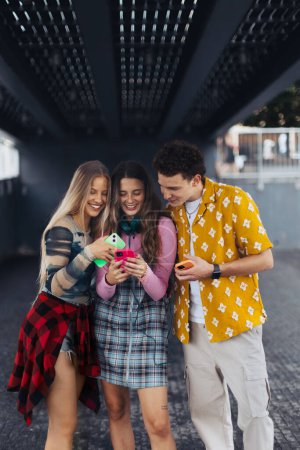 Photo for Generation z students hanging out together outdoors in the city. Young stylish zoomers are online, using smartphones, social media, taking selfies. Concept of power of friendship and social strength - Royalty Free Image