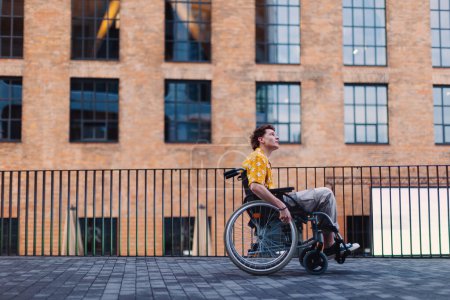 Photo for Gen Z boy in a wheelchair in the city. Inclusion, equality, and diversity among Generation Z. - Royalty Free Image