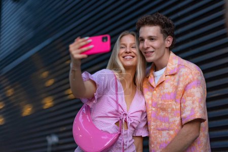 Foto de Gen Z pareja en traje rosa tomar selfie antes de ir al cine a ver la película. La joven niña y el niño del zoomer vieron una película que abordaba el tema de las mujeres, su posición en el mundo y su imagen corporal. - Imagen libre de derechos