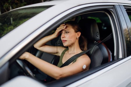 Mujer con diabetes sintiéndose mareada durante el viaje en coche. La mujer diabética con CGM necesita elevar su nivel de azúcar en sangre para continuar conduciendo.