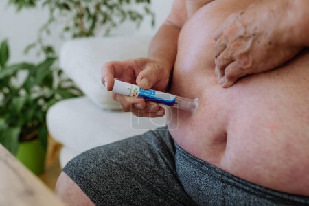 Téléchargez les photos : Homme en surpoids avec diabète injectant de l'insuline dans son abdomen. Gros plan de l'homme atteint de diabète de type 1 prenant isolant avec stylo isolant. - en image libre de droit