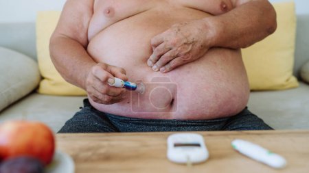 Photo for Overweight man with diabetes injecting insulin in his abdomen. Close up of man with type 1 diabetes taking insuling with insuling pen. - Royalty Free Image