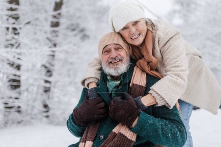 Photo for Close-up of elegant senior man with his wife in the snowy park, during cold winter snowy day. Elderly couple spending winter vacation in the mountains. Wintry landscape. - Royalty Free Image