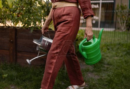 Foto de Un primer plano de una regadera. El jardinero sosteniendo una regadera de plástico y metal. - Imagen libre de derechos