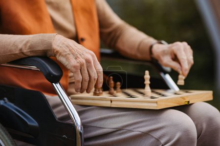 Foto de Primer plano del hombre mayor jugando al ajedrez al aire libre solo. Cliente de hogar de ancianos, disfrutando de un juego de ajedrez solitario, rompecabezas de ajedrez. - Imagen libre de derechos