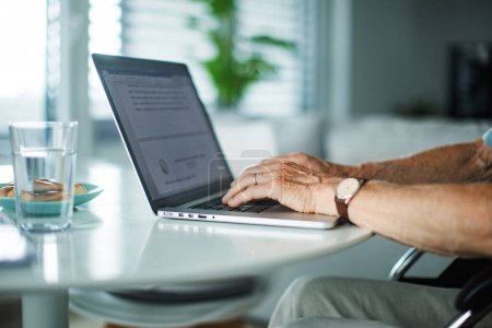 Nahaufnahme der Hände eines älteren Mannes, der auf einer Laptop-Tastatur tippt. Konzept der Arbeit von zu Hause aus.
