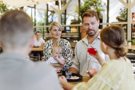 Photo for Big family with children and a small baby at family dinner in a restaurant. A small family celebration in family friendly restaurant. - Royalty Free Image