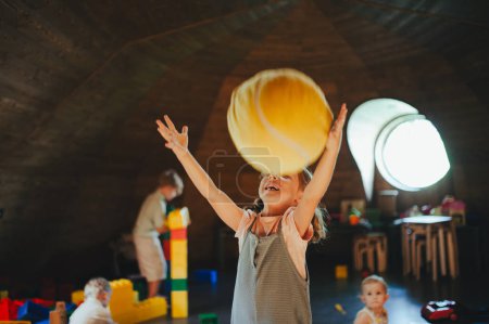 Mädchen fangen großen flauschigen Ball. Kinder spielen gemeinsam in einem Indoor-Spielplatz in einem Restaurant oder Hotel. Konzept des kinderfreundlichen Restaurants.