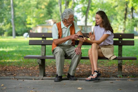 Foto de Cuidador ayudando a un hombre mayor a comprar en línea en un teléfono inteligente. El riesgo de estafas de compras en línea dirigidas a las personas mayores. - Imagen libre de derechos