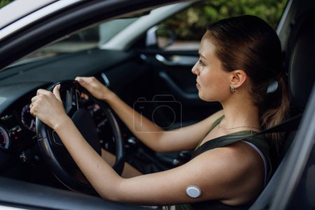 Photo for Woman with diabetes monitoring her blood sugar during car drive. Diabetic woman with CGM needs to raise her blood sugar level to continue driving. - Royalty Free Image