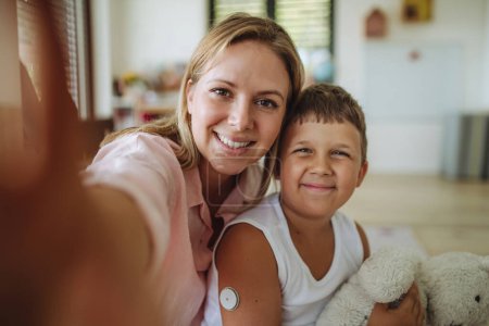 Photo for Selfie portrait of mother and diabetic boy with a continuous glucose monitor on his arm. The CGM device makes the life of the schoolboy easier, helping manage his illness and focus on other activities - Royalty Free Image