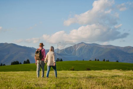 Photo for Senior couple walking through the autumn nature. Elderly spouses enjoying the beautiful view of the High Tatras. Minimalist landscape photography with copy space. - Royalty Free Image