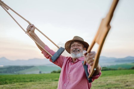 Photo for Senior man holding crutches in the air, he is happy about his recovery. Recovery, rehabilitation after injury or surgery in the nature. Concept of recovery and physical therapy - Royalty Free Image