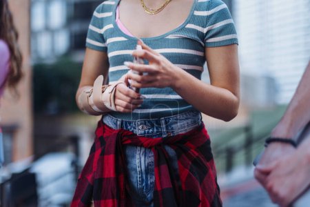Photo for Close up of a young womans injured wrist with a plastic brace on. Gen z girl in trendy outfit. - Royalty Free Image