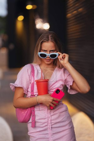 Photo for Portrait of gen Z girl in pink outfit before going the cinema to watch movie. The young zoomer girl watched a movie addressing the topic of women, her position in the world, and body image. - Royalty Free Image