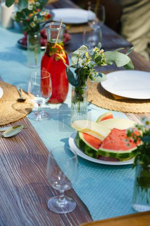 Téléchargez les photos : Gros plan d'une table dressée lors d'une garden party estivale. Cadre de table avec verres, limonade, limonade aux fruits frais et décoration florale délicate. - en image libre de droit